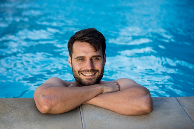 Portret van lachende jonge man ontspannen in het zwembad