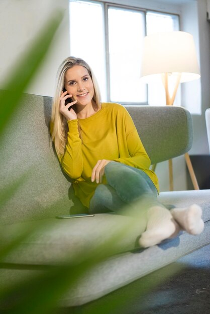 Portret van lachende jonge vrouw aan de telefoon thuis