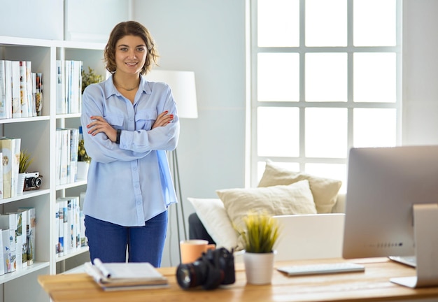 Portret van lachende jonge vrouw met dslr fotocamera staande in loft appartement