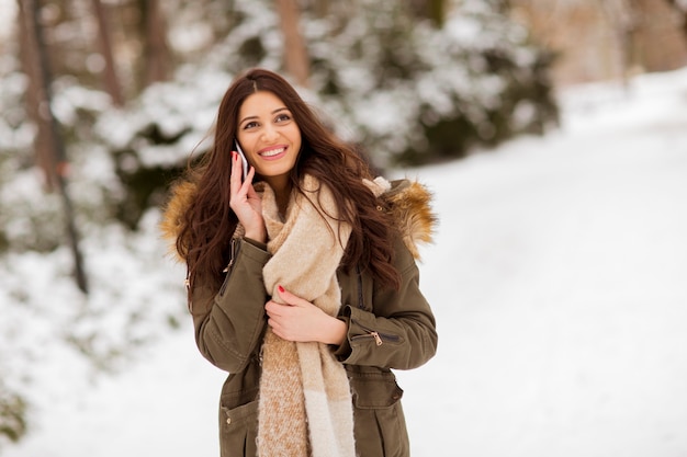 Portret van lachende jonge vrouw met mobiele telefoon in de winter buiten