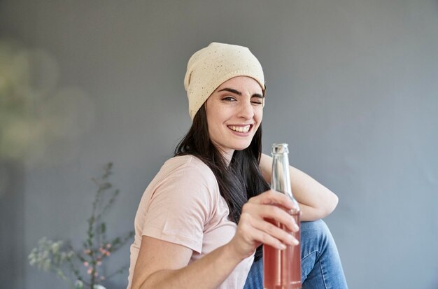 Foto portret van lachende jonge vrouw twinkelende fles houden