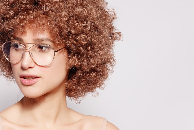 Portret van lachende jonge zwarte vrouw. Portret van een mooie jonge vrouw met Afro-Amerikaanse afro kapsel en glamour make-up. Studio opname. Aantrekkelijk meisje dat oogglazen draagt.