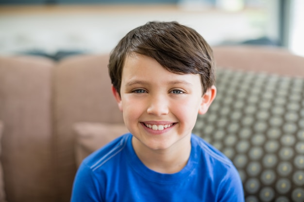 Portret van lachende jongen zittend op de bank in de woonkamer