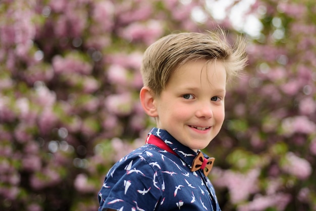 Portret van lachende kind gelukkige jongen in een kleurrijke bloeiende sakura lente