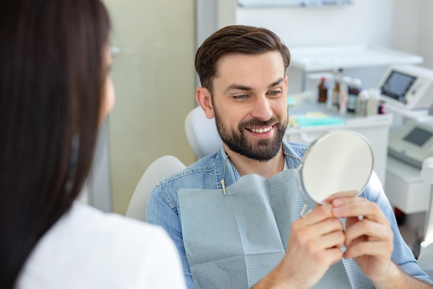 Portret van lachende klant die tanden in de spiegel bekijkt