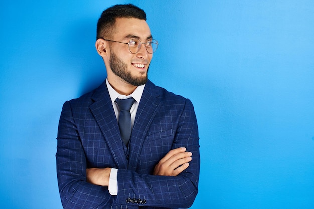 Portret van lachende knappe succesvolle Kazachse Aziatische zakenman in pak met armen gekruist op blauwe studio achtergrond, geïsoleerd met kopie ruimte