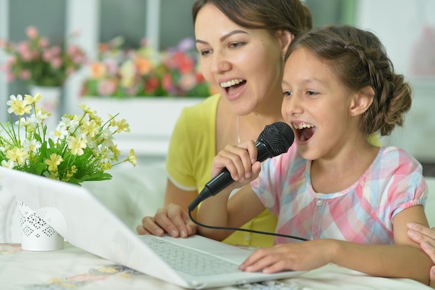 Foto portret van lachende moeder en dochter die karaoke zingen