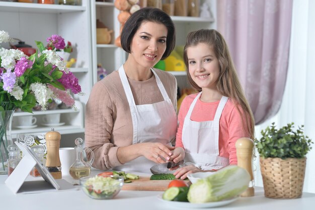 Portret van lachende moeder en dochter die samen koken in de keuken