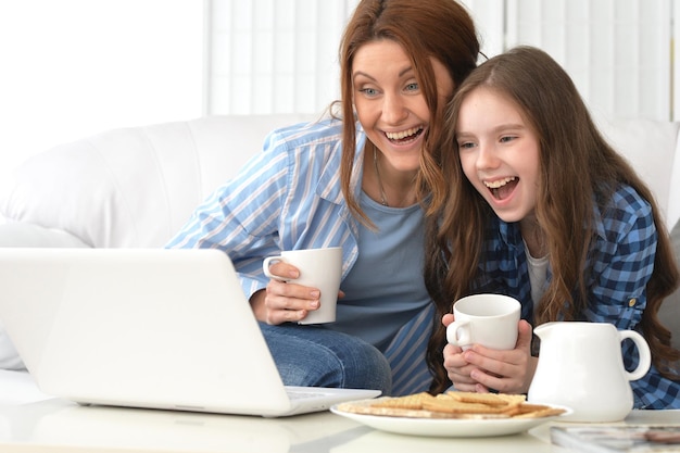 Portret van lachende moeder en dochter met laptop thuis