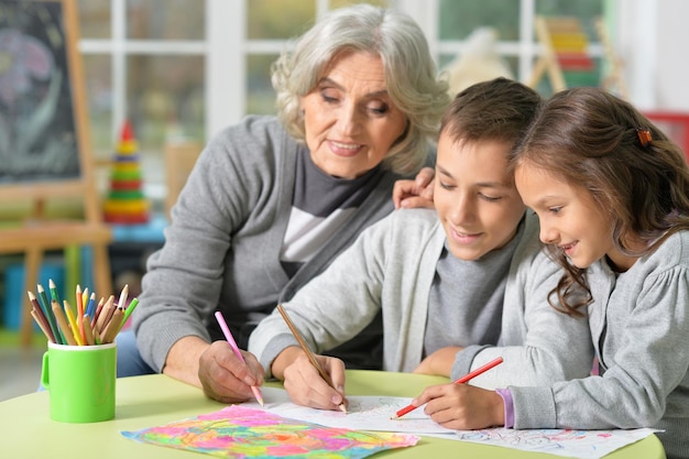 Portret van lachende oma met kinderen die samen tekenen