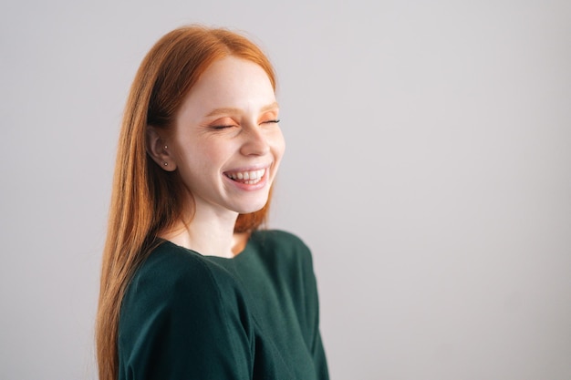 Portret van lachende roodharige jonge vrouw model met gesloten ogen op witte achtergrond Medium shot van vrolijke gelukkig roodharige dame met natuurlijke schoonheid poseren in professionele studio