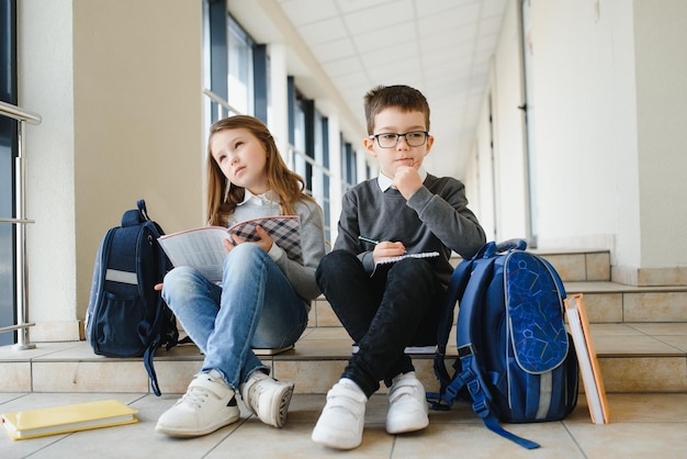 Portret van lachende schoolkinderen in schoolgang met boeken