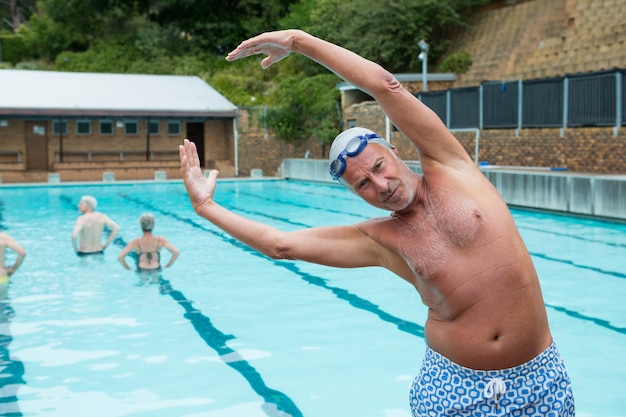 Portret van lachende senior man excerising bij zwembad