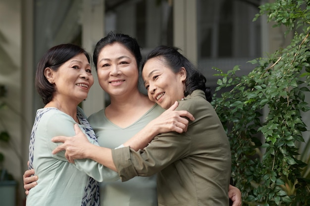 Portret van lachende senior vrouwen knuffelen en kijken naar camera oude vrienden reünie concept