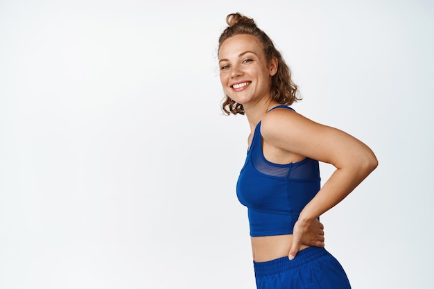 Portret van lachende Sportvrouw in activewear. Fitness vrouw die er gelukkig uitziet na de training, staande op wit