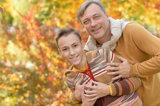 Portret van lachende vader en zoon knuffelen in herfst park