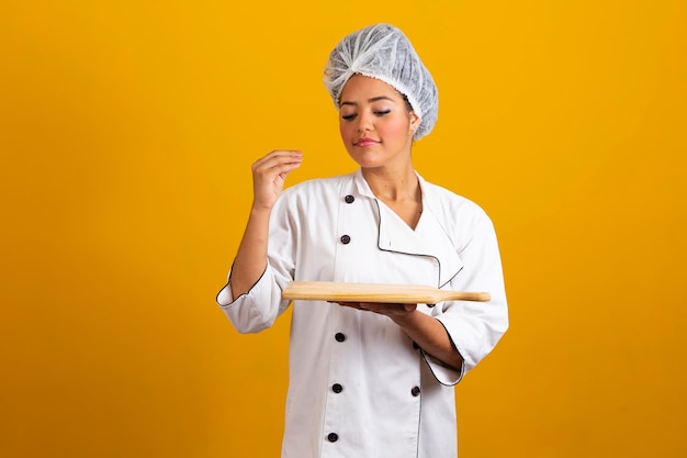 Portret van lachende vrouw chef-kok met snijplank geïsoleerd op gele achtergrond