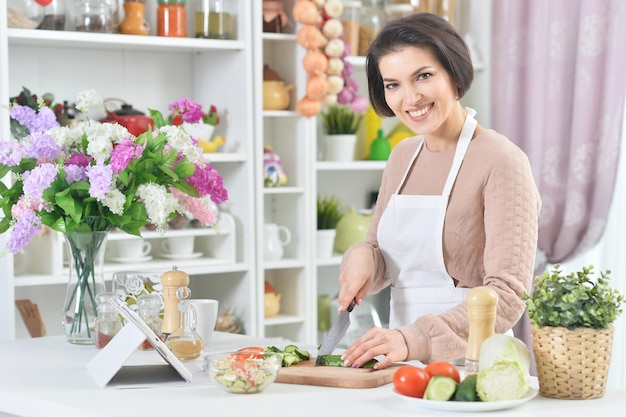 Portret van lachende vrouw die kookt in de keuken