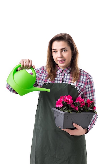 Portret van lachende vrouw professionele tuinman of bloemist in schort met bloemen in een pot en tuingereedschap geïsoleerd op een witte achtergrond