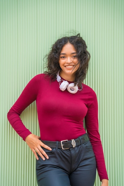 Portret van Latijns-vrouw met koptelefoon glimlachend technologie concept op een groene achtergrond student op de campus