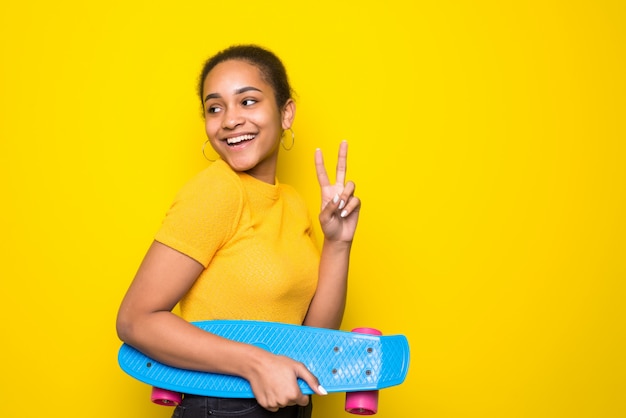 Portret van Latijnse jonge vrouw die geel skateboard houdt. Mensen levensstijl concept.