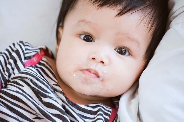 Portret van leuk Aziatisch babymeisje die camera met vuile mond bekijken