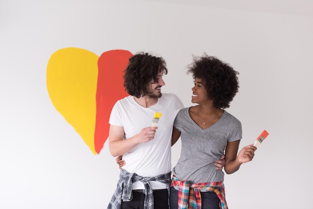 Portret van liefdevol multi-etnisch koppel met geschilderd hart op de muur