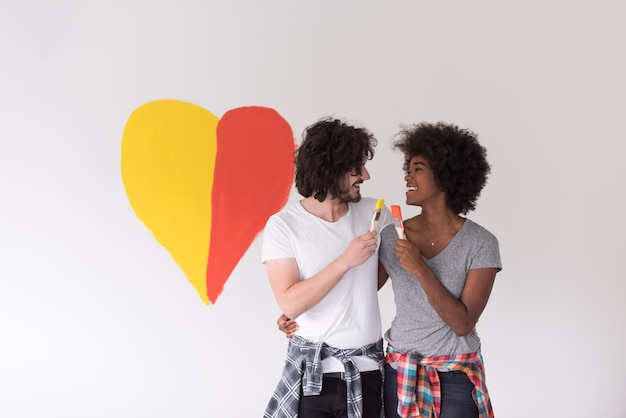 Portret van liefdevol multi-etnisch koppel met geschilderd hart op de muur