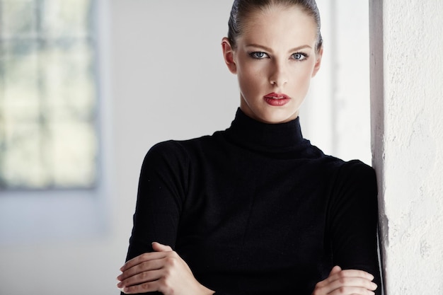 Portret van luxe brunette vrouw in zwarte trui over lichte achtergrond.