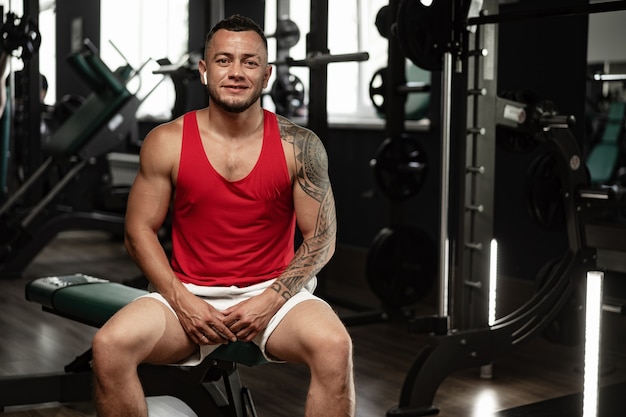 Portret van man bodybuilder in rood shirt in sportschool