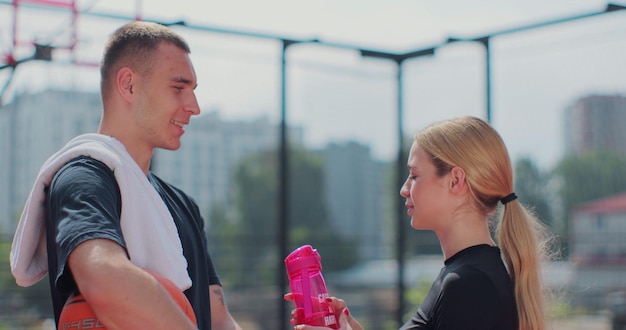 Portret van man en vrouw vrienden op basketbalveld na training praten na het sporten en kijken naar de camera Concept van sport power competitie actieve levensstijl