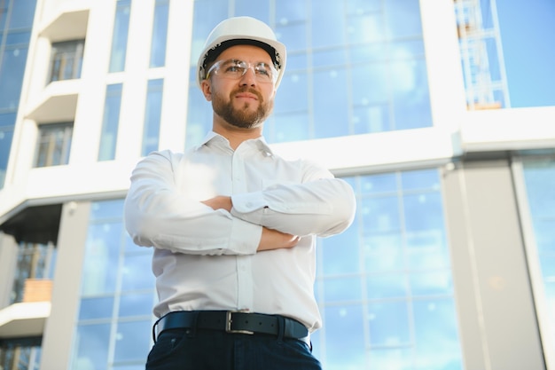 Portret van man ingenieur op bouwplaats. mannelijke bouwmanager met witte helm en geel veiligheidsvest