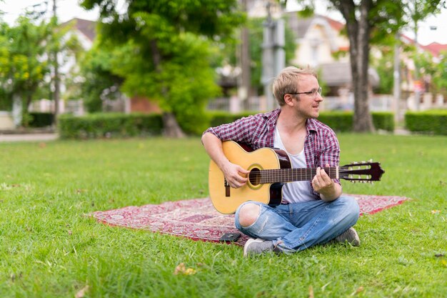 Portret van man met picknick tijdens het spelen van de gitaar buitenshuis