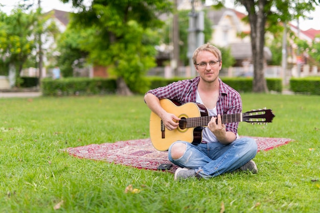 Portret van man met picknick tijdens het spelen van de gitaar buitenshuis