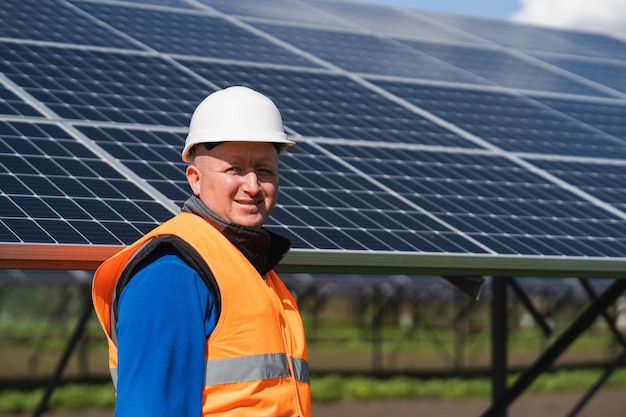 Portret van mannelijke elektrotechnisch ingenieur op de achtergrond van zonnepanelen bij een elektriciteitscentrale