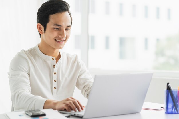 Portret van mannelijke werknemer die aan computer met gelukkige uitdrukking werkt