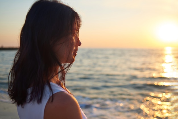 Portret van meisje die op mooie overzeese zonsondergang kijken.