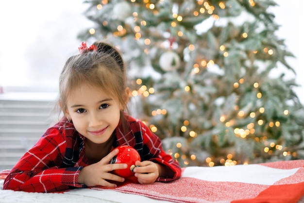 Portret van meisje in geruite pyjama met kerstbal