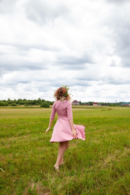 Portret van meisje in roze jurk met krans van wilde bloemen