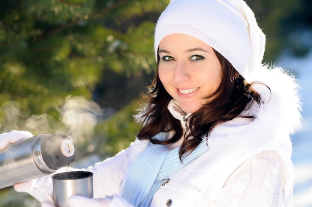 Portret van meisje in witte hoed en handschoenen houdt metalen beker in de buurt van het gezicht