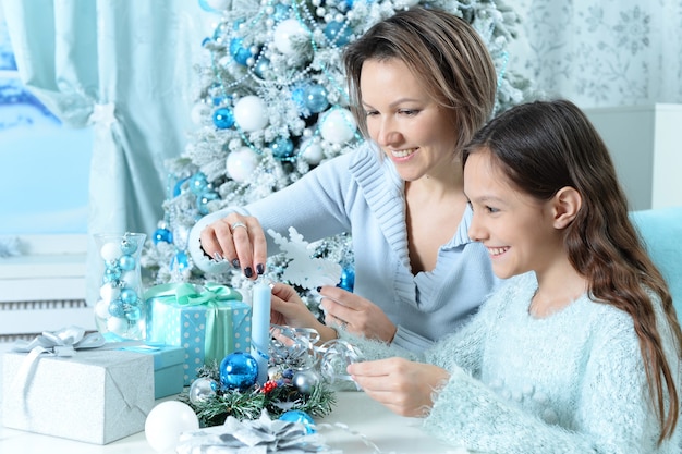 Portret van meisje met haar moeder die zich voorbereidt op Kerstmis