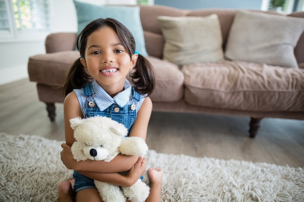 Portret van meisje met teddybeerzitting in woonkamer