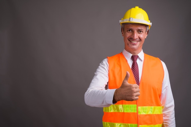 Portret van mensenbouwvakker tegen grijze muur