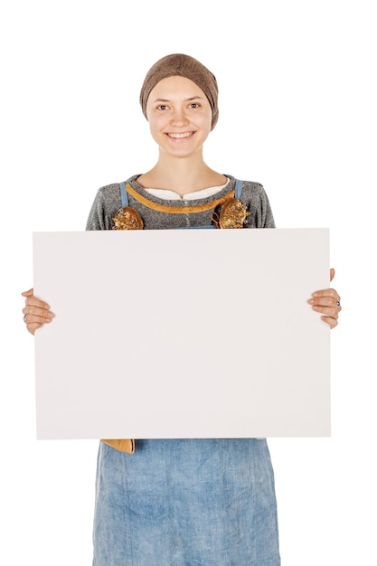 Portret van middeleeuwse slavische vrouw die een leeg uithangbord van het blocnote witte bord houdt dat een leeg aanplakbord toont tegen een wit studio achtergrond historisch concept