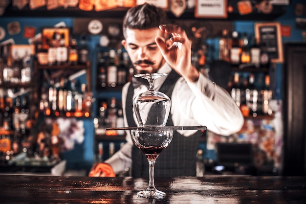 Portret van mixologist demonstreert het proces van het maken van een cocktail terwijl je bij de bar in de nachtclub staat