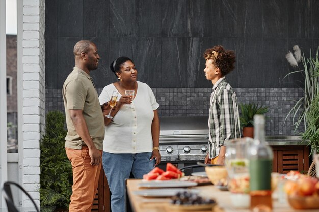 Portret van moderne Afro-Amerikaanse familie met tienerzoon genieten van diner op terras kopiëren s...