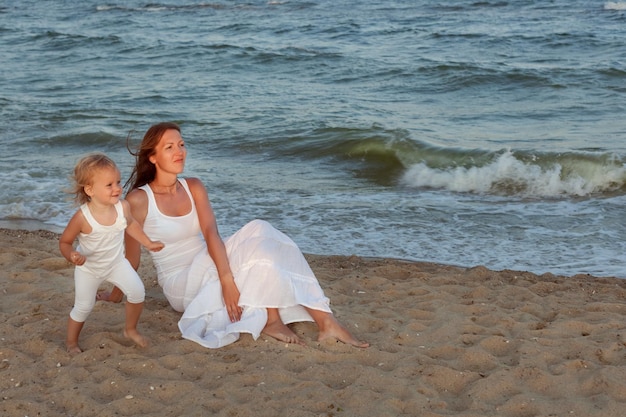 Portret van moeder en dochter aan de kust Ze zitten in het zand