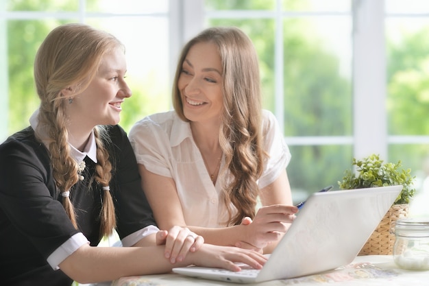 Foto portret van moeder en dochter met laptop thuis