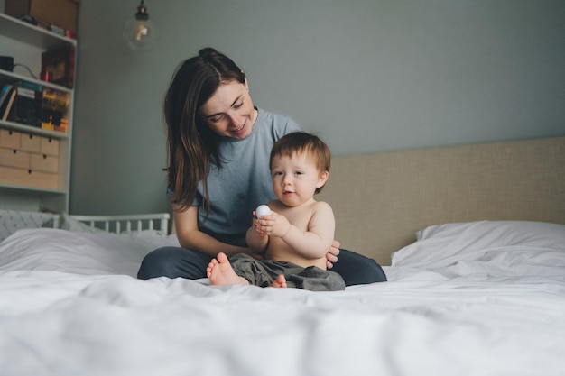 portret van moeder en kind op het bed in de slaapkamer met een witte sprei