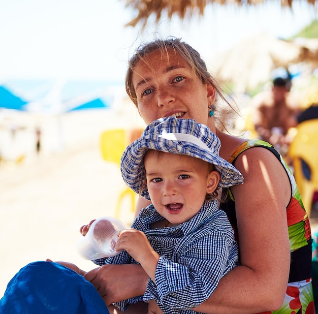 Portret van moeder en zoon die op het strand zitten